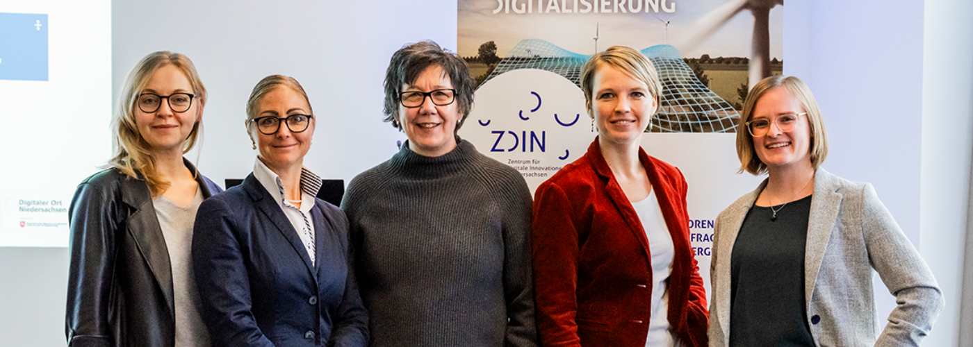 Vier Frauen stehen nebeneinander und schauen in die Kamera.