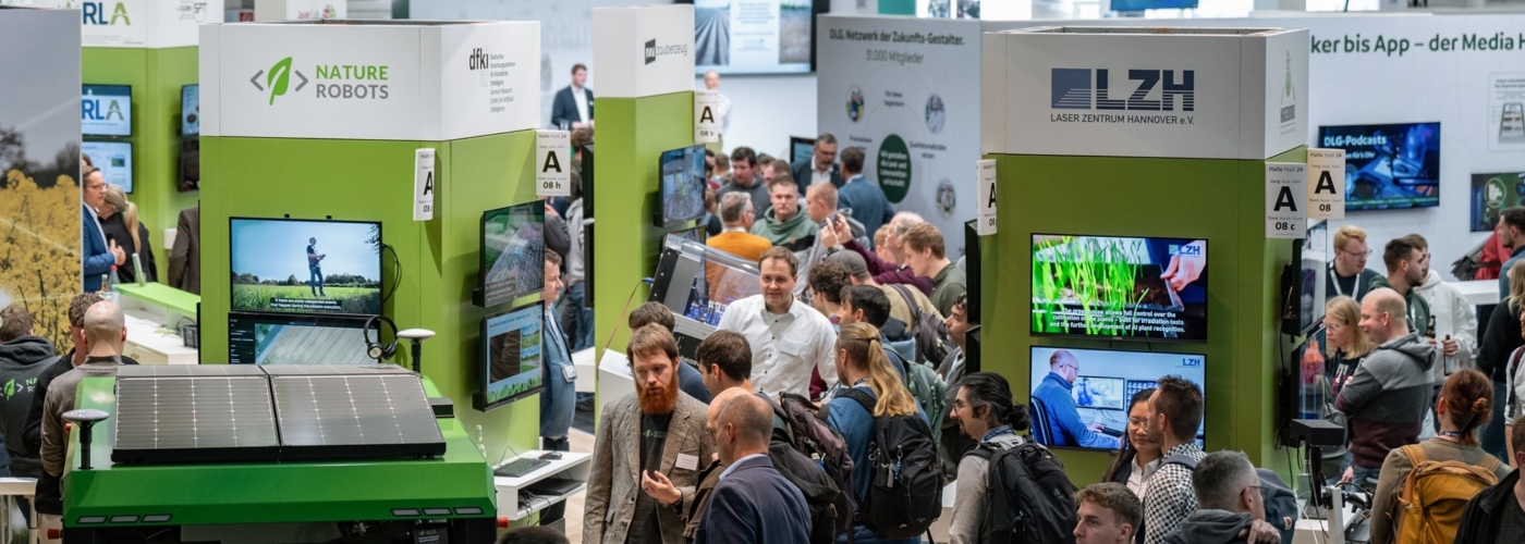 Viele Menschen unterhalten sich an einem Messestand.