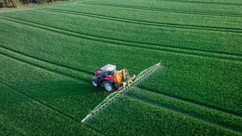 Traktor mit Feldspritze auf einem Acker