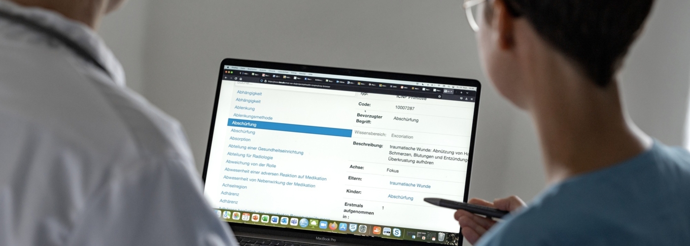 Zwei Personen schauen auf einen Laptop, auf dem eine Online-Umfrage zu sehen ist.