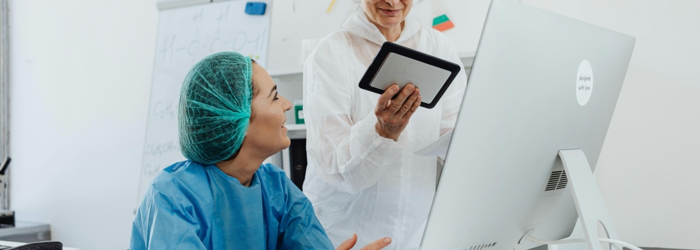 Zwei Frauen in medizinischer Kleidung schauen auf ein Tablet