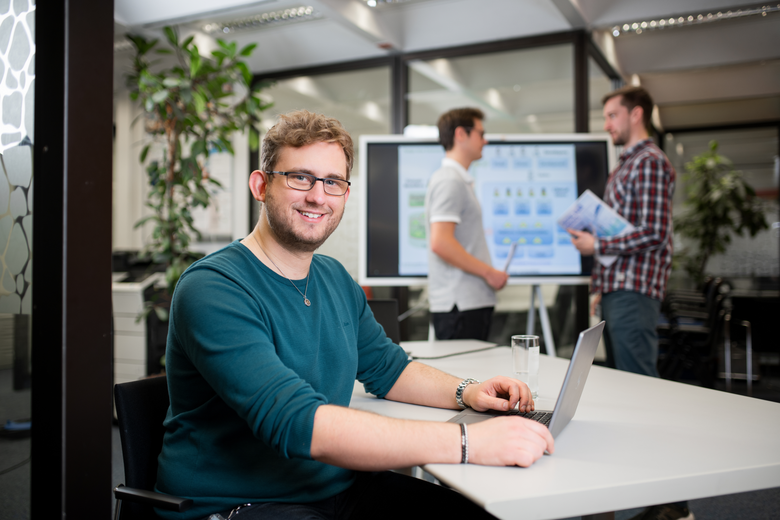 Mann sitzt lächelnd an einem Schreibtisch