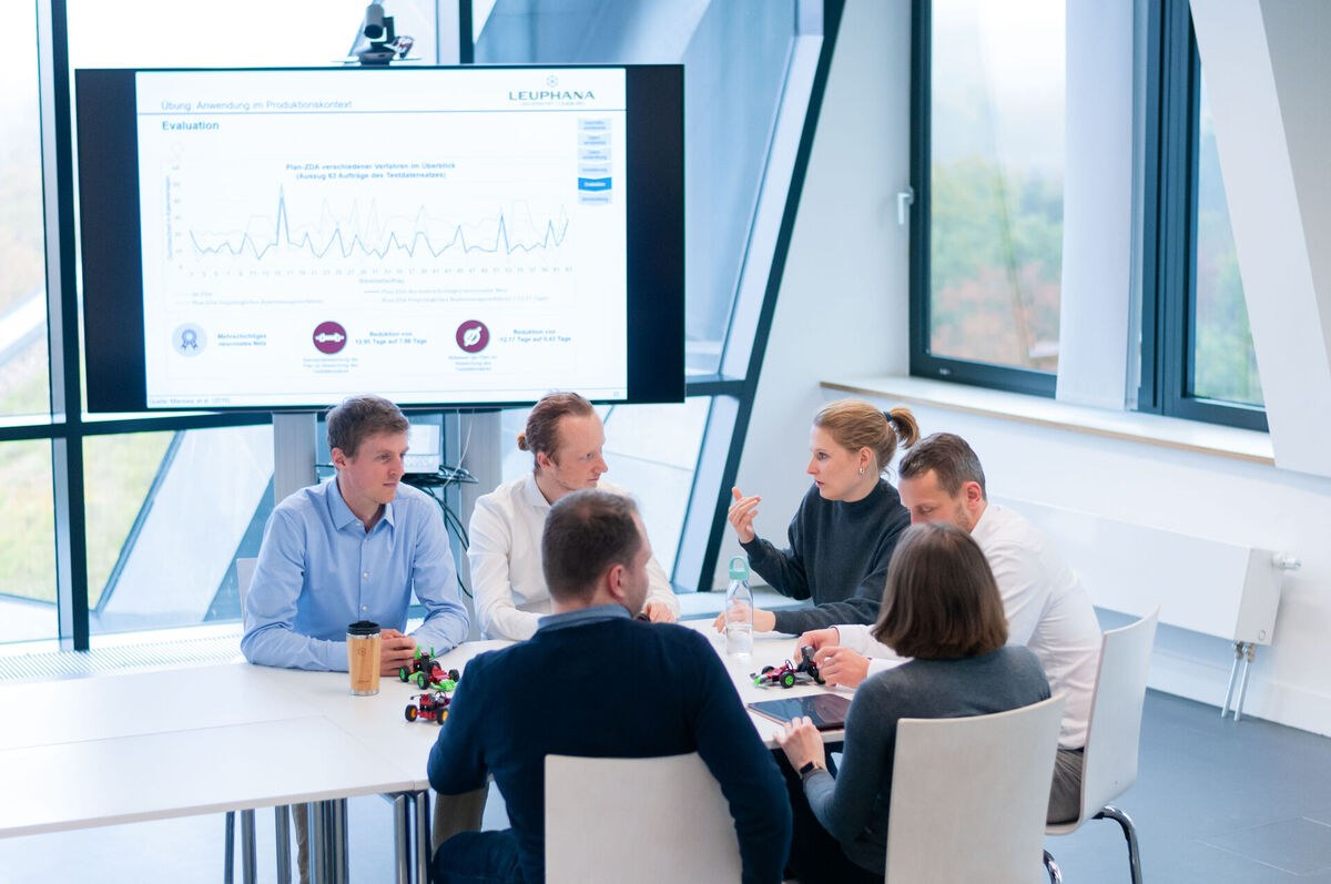Mehrere Personen sitzen an einem Konferenztisch und diskutieren