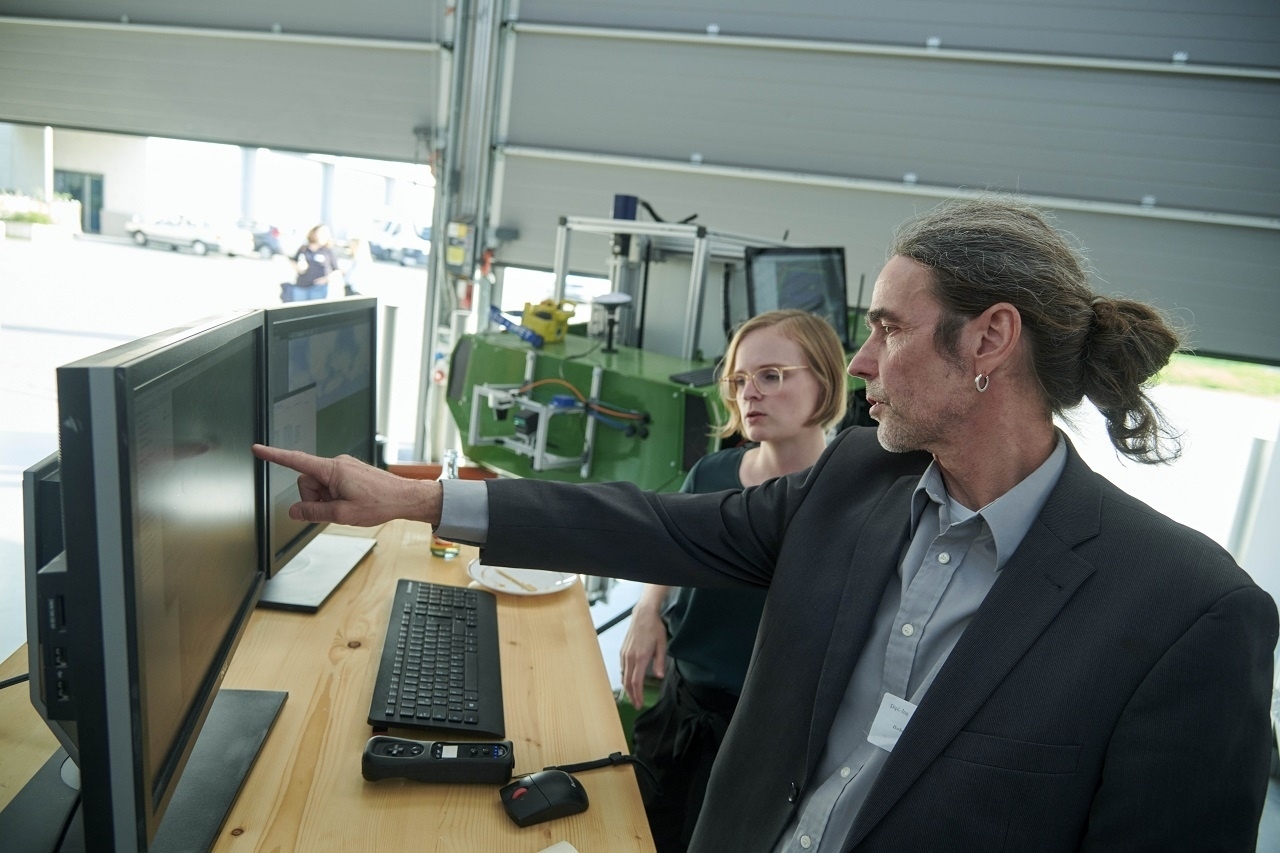 Zwei Personen stehen vor einem Computer