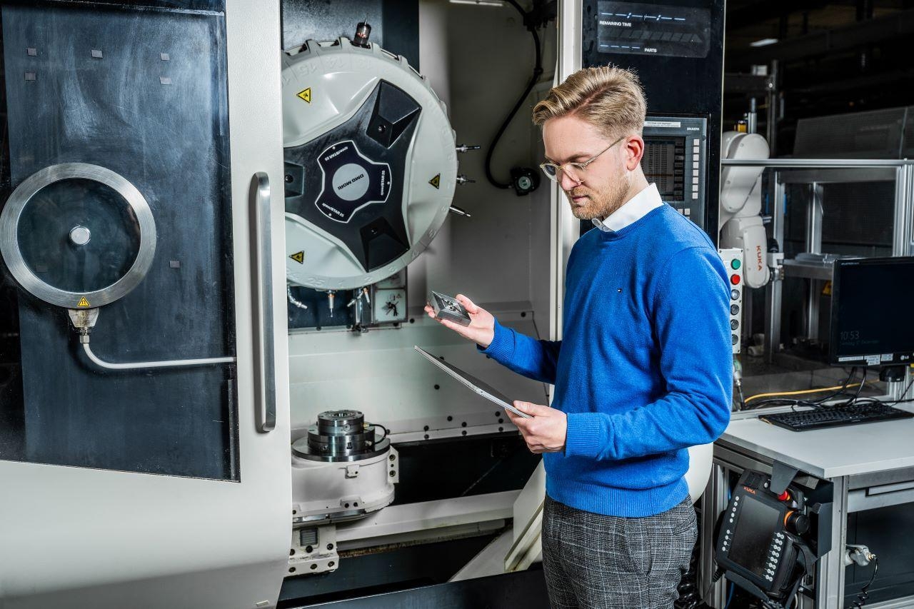 Mann steht prüfend neben einer Produktionsmaschine