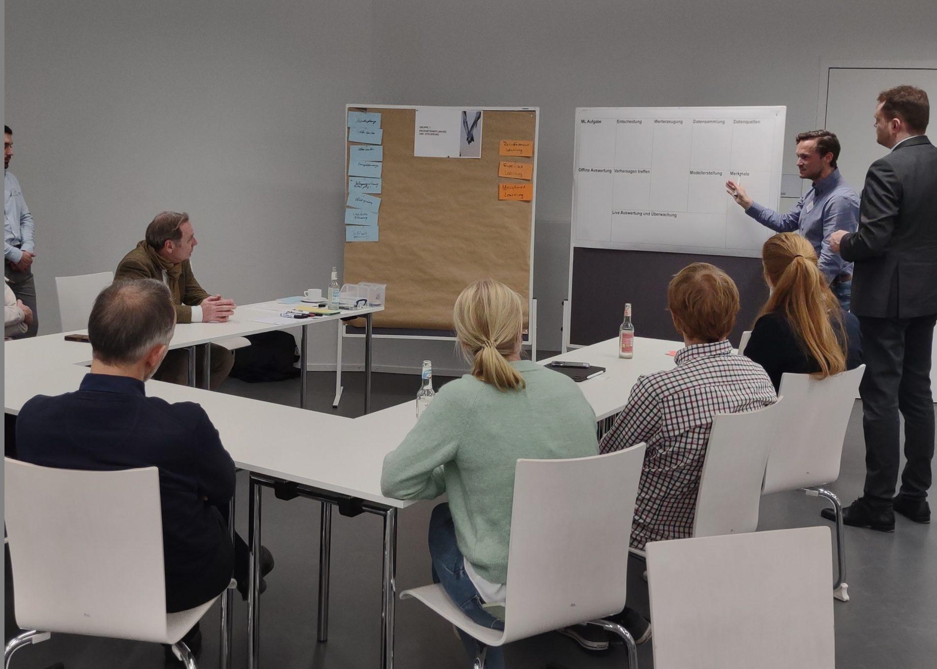 Menschen sitzen in Seminarraum und hören Vortrag zu.