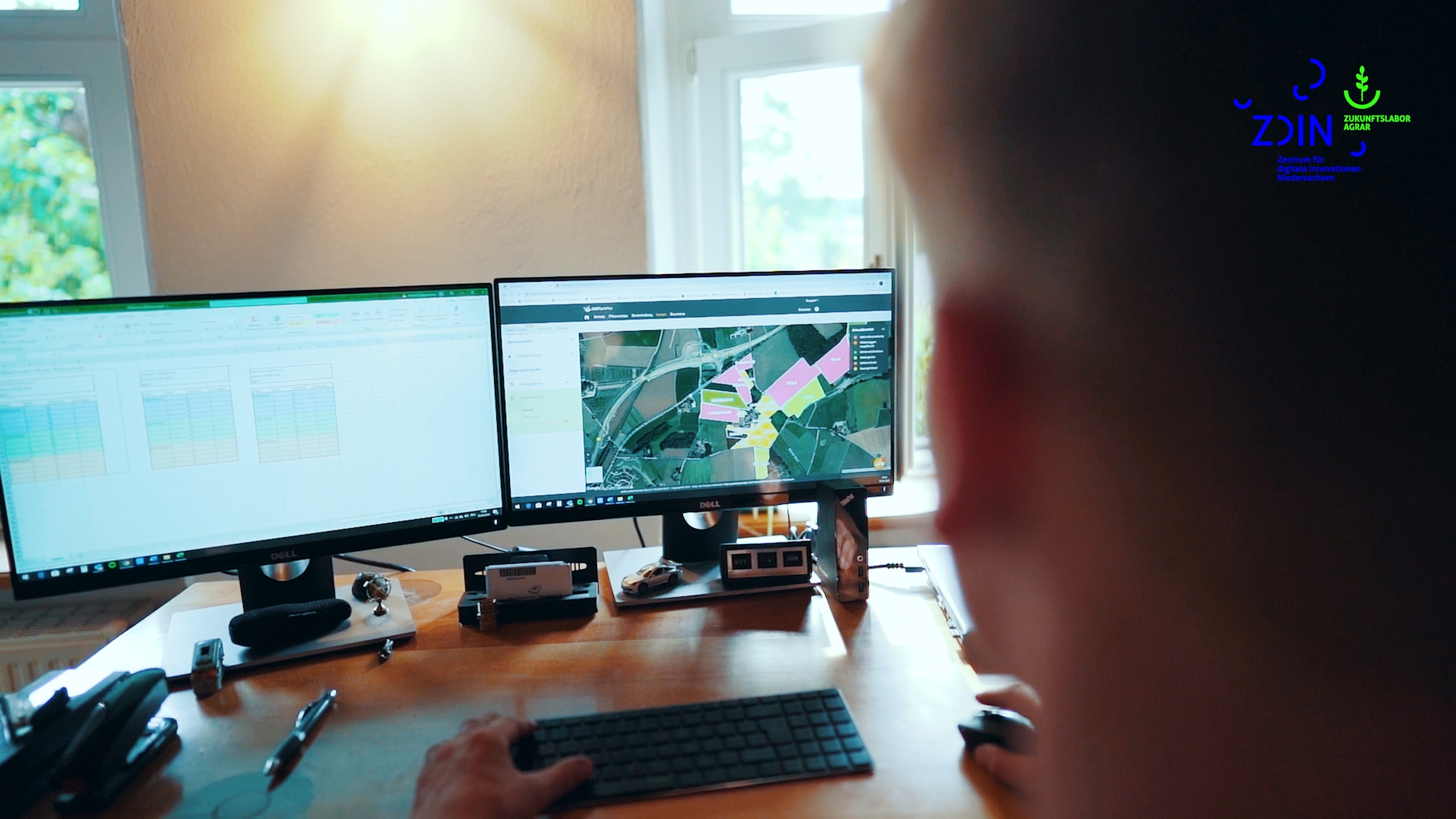 Person sitzt an einem Schreibtisch mit PC-Bildschirm