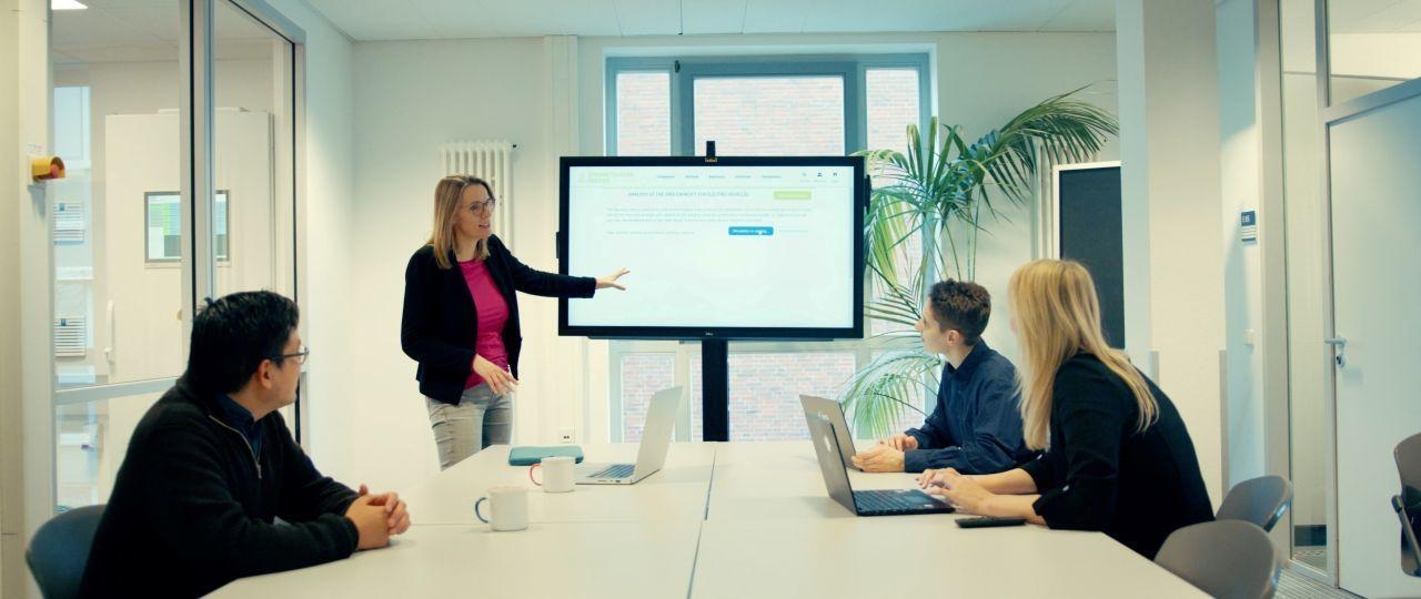 Vier Personen in einem Konferenzraum.