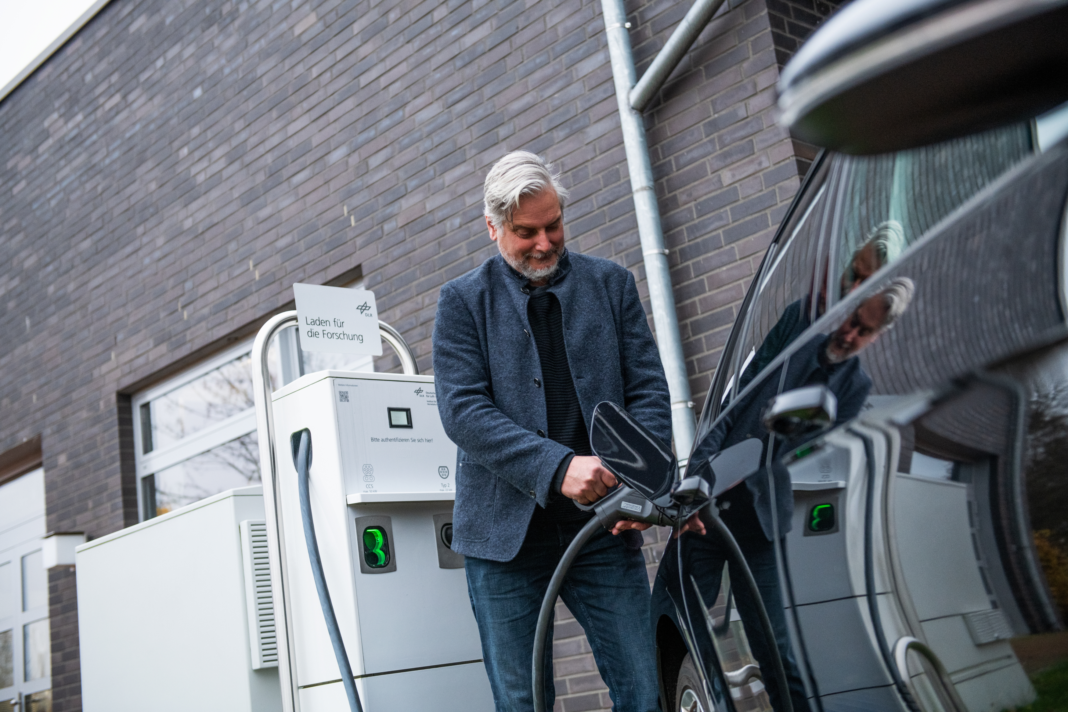 Mann lädt ein Elektrofahrzeug an einer Ladesäule