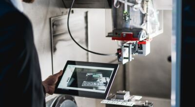 Mann steht mit Tablet vor einer Maschine