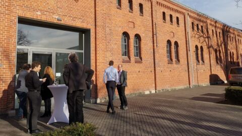 Eine kleine Personengruppe steht vor einem Gebäude