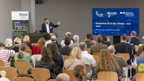 Ein Mann am Rednerpult hält einen Vortrag vor einem Publikum.