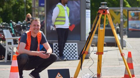 Mann mit Warnweste hockt neben einem Verkehrsmessgerät