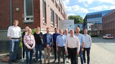 Eine Menschengruppe steht am Escherweg 2 und blickt in die Kamera