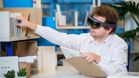 Mann hat eine dicke technische Brille auf und arbeitet an einem Schreibtisch