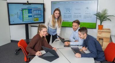 Mehrere Personen sitzen mit Laptop an Tisch