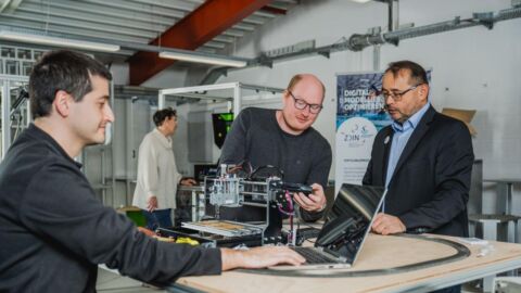 Drei Männer sind in einem Labor und diskutieren über einen technischen Demonstrator.