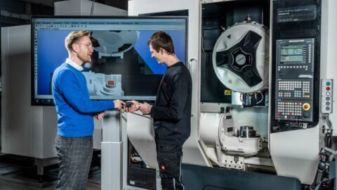 Zwei Personen stehen in einem Maschinenraum vor einem Bildschirm