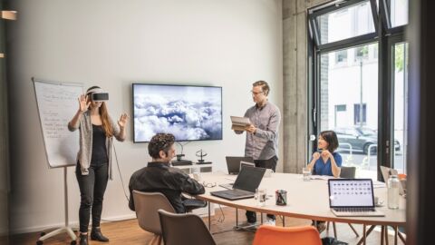 Personen in Raum mit Frau, die eine AR-Brille trägt