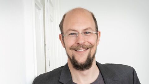 Ein Mann mit Bart lächelt in die Kamera.