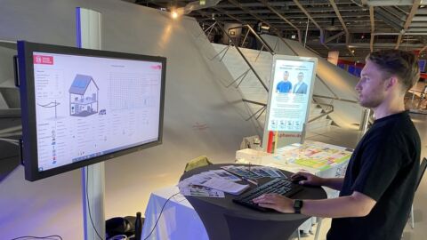 Ein Mann steht vor einem Bildschirm, auf dem ein Energiemanager für ein Hauses abgebildet ist