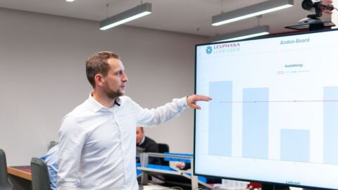 Ein Mann steht vor einem Bildschirm mit Balkendiagrammen