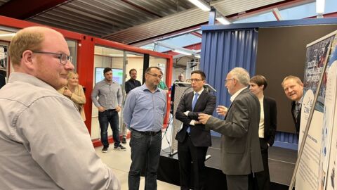 Eine Personengruppe steht vor einem Rednerpult und unterhält sich