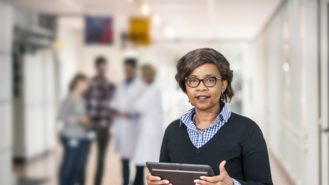 Frau mit Tablet in der Hand blickt in die Kamera