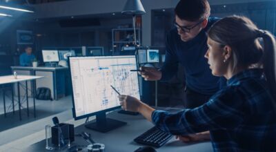 Zwei Personen besprechen etwas an einem Computer-Bildschirm