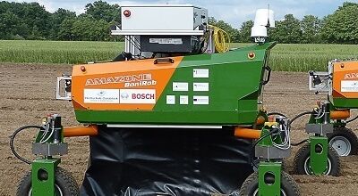 Der grün orangene Agrarroboter auf einem Feld