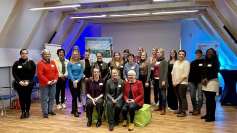 Eine große Frauengruppe mit Namensschildern blickt in die Kamera.