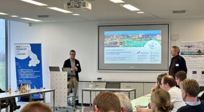 Mehrere Personen sitzen in einem Raum und hören einer Präsentation zu