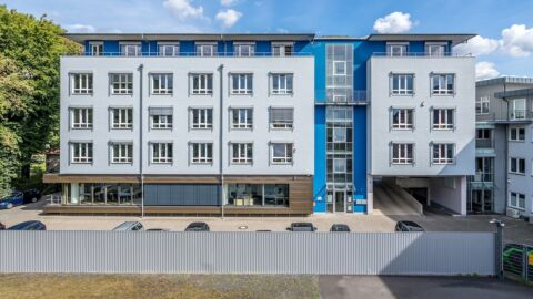 Bild eines hellblauen vierstöckigen Gebäudes.