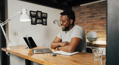 Ein Mann sitzt am Tisch vor einem Laptop