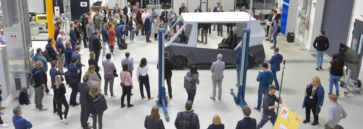 Eine Menschengruppe steht vor dem Prototypen eines Autos.