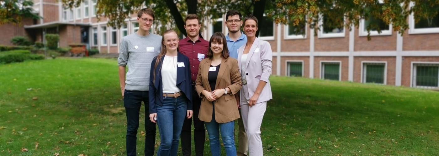 Eine kleine Personengruppe blickt in die Kamera