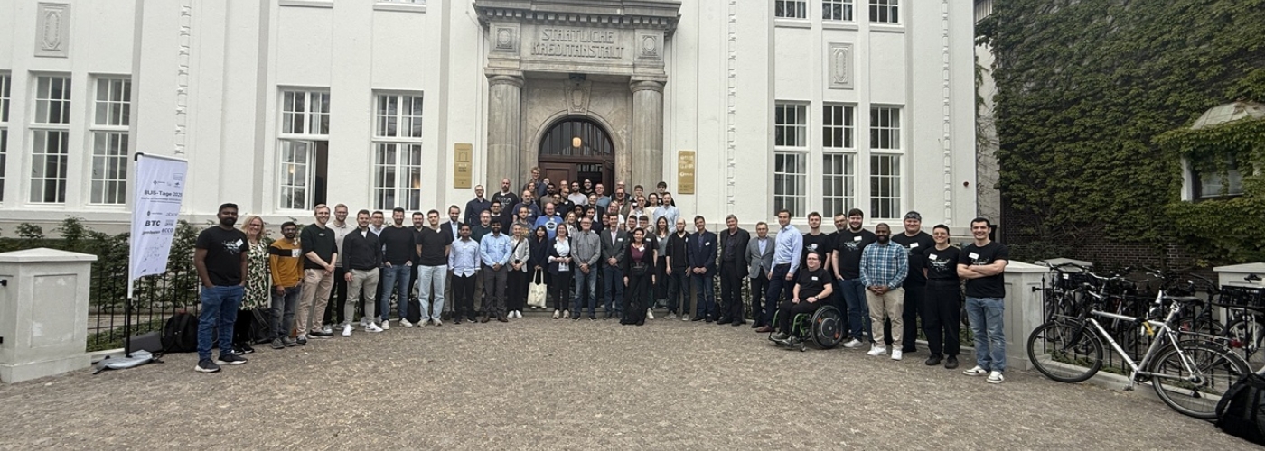 Eine Gruppe von Menschen steht auf dem Hof vor einem weißen Gebäude.