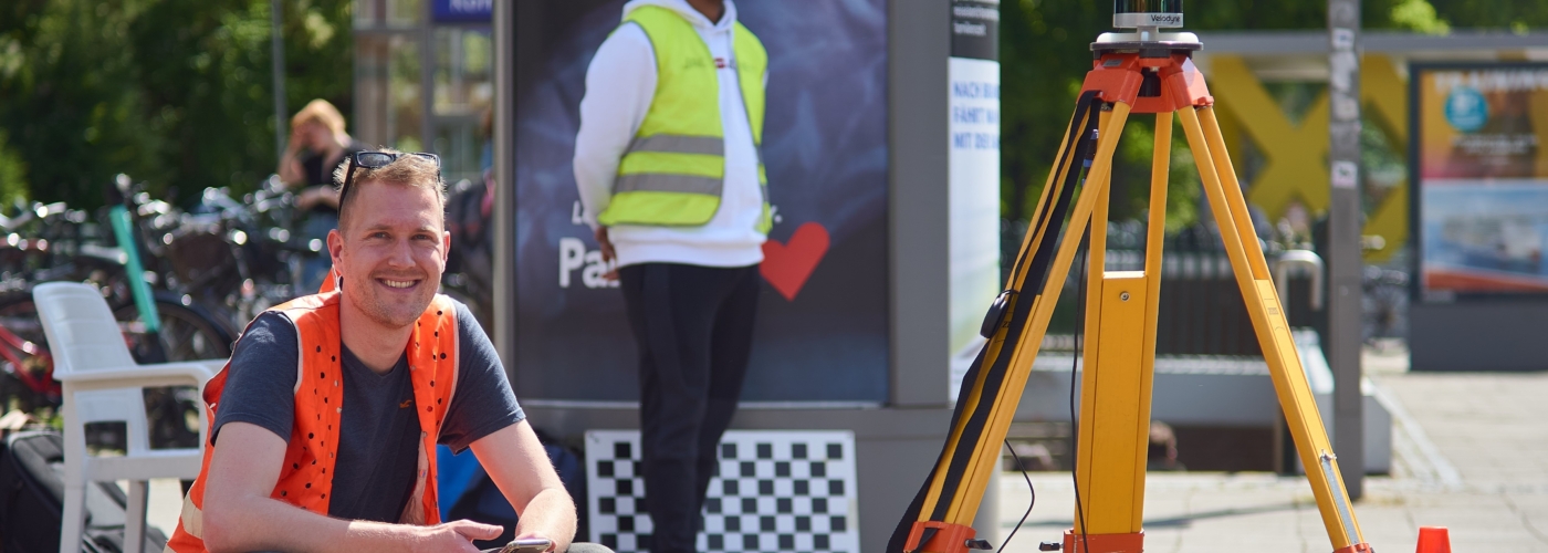 Mann mit Warnweste hockt neben einem Verkehrsmessgerät