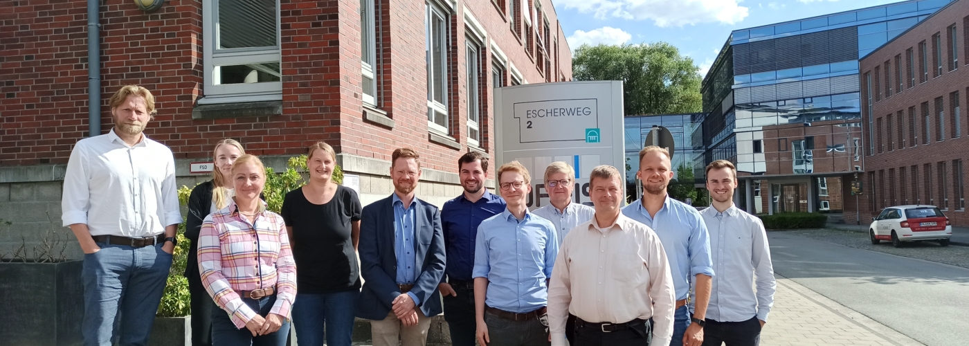 Eine Menschengruppe steht am Escherweg 2 und blickt in die Kamera