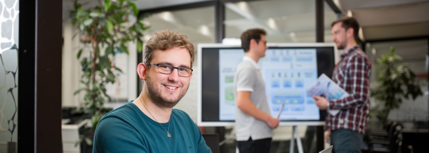 Mann sitzt am Tisch und bedient Laptop