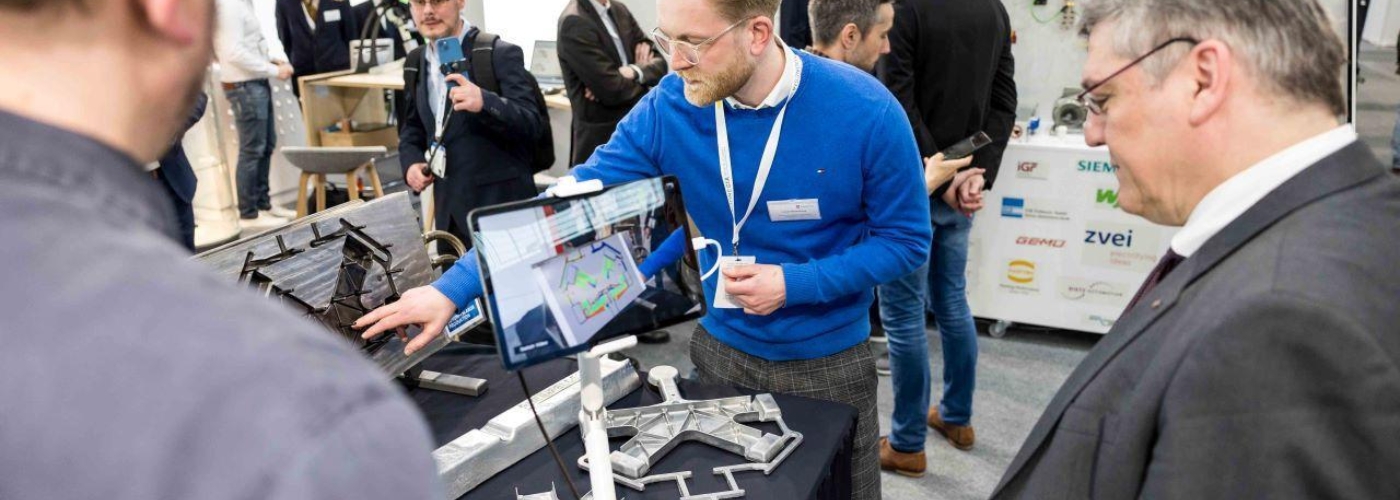 Mann erklärt auf einem Messestand ein technisches Vorgehen