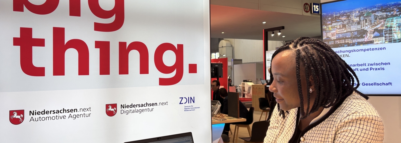 Eine Frau präsentiert an einem Messestand etwas auf einem Laptop.