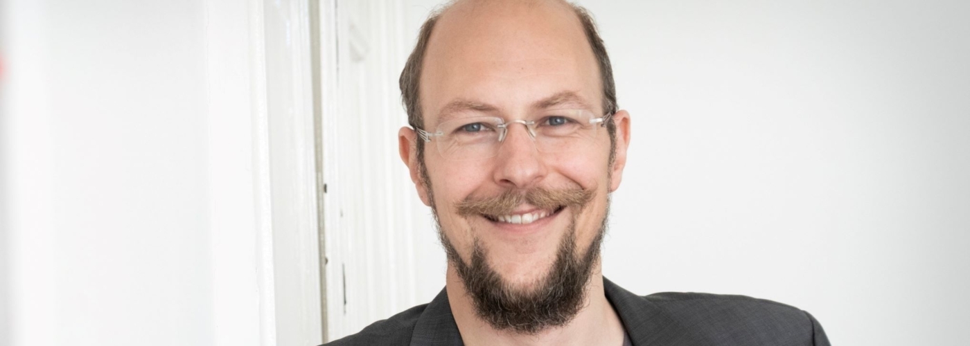 Ein Mann mit Bart lächelt in die Kamera.