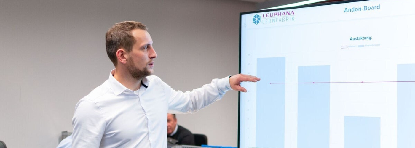 Ein Mann steht vor einem Bildschirm mit Balkendiagrammen