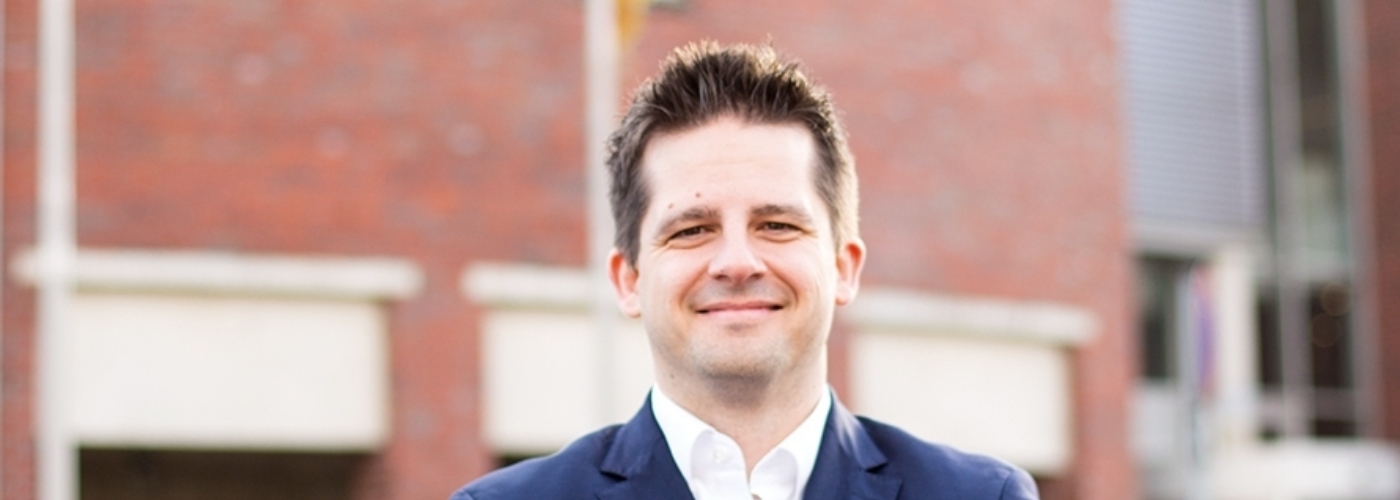 Prof. Dr. Sebastian Lehnhoff steht mit verschränkten Armen lächelnd vor dem OFFIS Gebäude