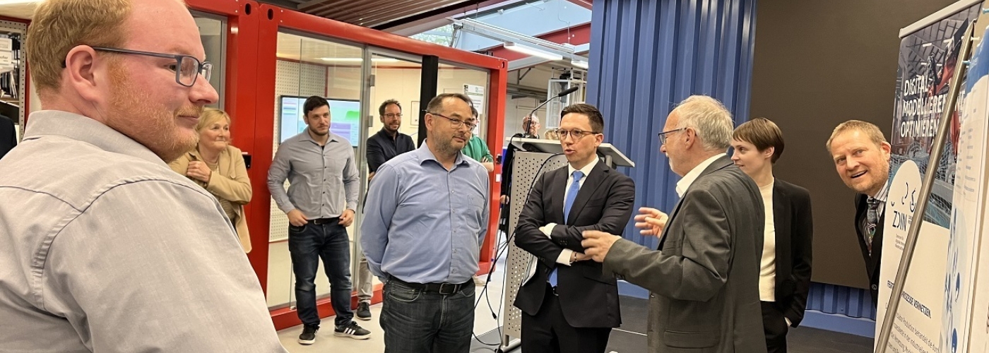 Eine Personengruppe steht vor einem Rednerpult und unterhält sich