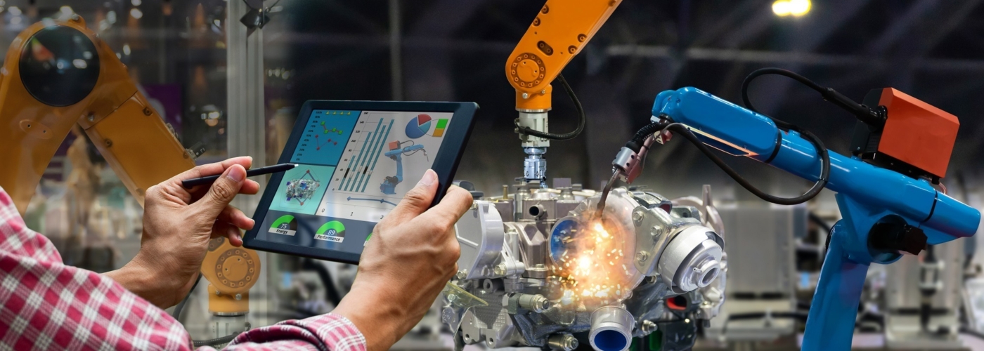 Person trägt Tablet und steht vor einer Maschine