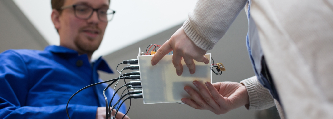 Zwei Personen blicken auf einen technischen Gegenstand