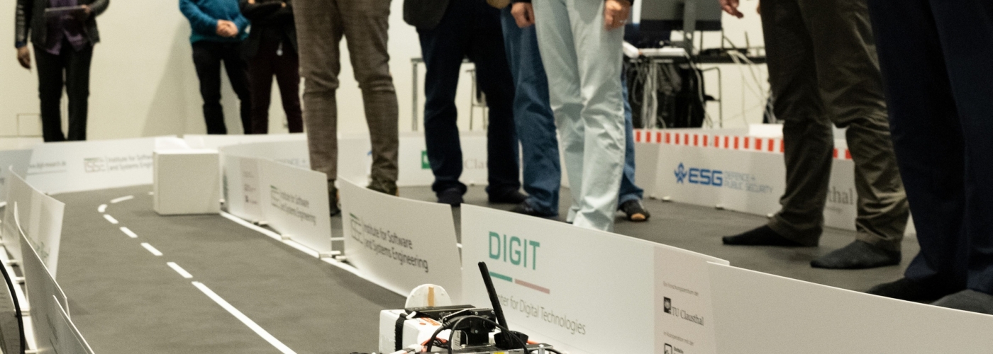 Beobachter stehen um einen Rennstrecke mit einem Modellauto herum