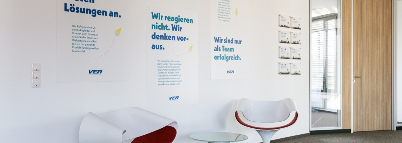 Moderne Stühle vor verschiedenen Plakaten.